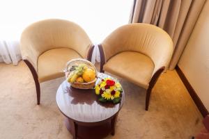 麦纳麦快乐时光酒店的两把椅子和一张桌子,上面放着一篮水果和鲜花