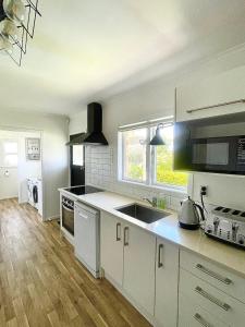 奥克兰Alta House的厨房配有白色橱柜、水槽和窗户。