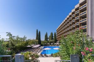 罗马MIDAS Palace Hotel - A member of Barcelo Hotel Group的一个带游泳池、遮阳伞和树木的度假村
