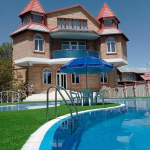 乔尔蓬阿塔Private Luxury Villa - Issyk Kul的一座带游泳池和蓝伞的房子