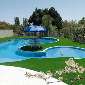 乔尔蓬阿塔Private Luxury Villa - Issyk Kul的游泳池旁带遮阳伞的桌子