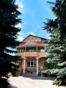 乔尔蓬阿塔Private Luxury Villa - Issyk Kul的一座有红色屋顶和两棵树的房子