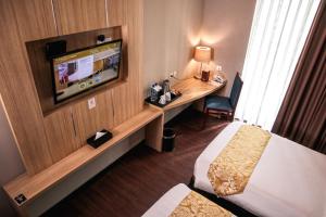 棉兰Anara Sky Kualanamu Hotel的配有电视、床和书桌的酒店客房