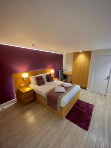 恩菲尔德霍尔特华特斯酒店的一间卧室设有一张大床和紫色的墙壁