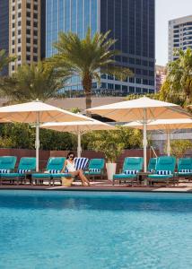 迪拜Jumeirah Emirates Towers Dubai的坐在游泳池旁椅子上的女人