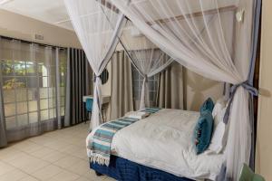 维多利亚瀑布Hungwe House的一间卧室配有带窗帘的天蓬床