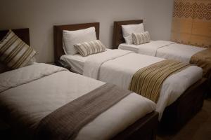 卡拉奇Xefan Hotels的带3张白色床单的床的房间