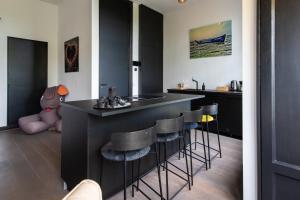 阿姆斯特丹Museum Square View B&B的厨房配有黑色橱柜和酒吧凳子