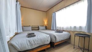 Sonai与那国むんぶステイ祖納的带窗户的客房内设有两张单人床。