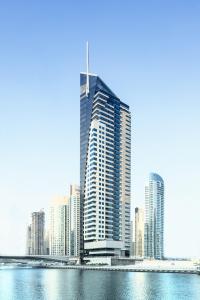 迪拜Dusit Princess Residences Dubai Marina的水体旁边的高楼