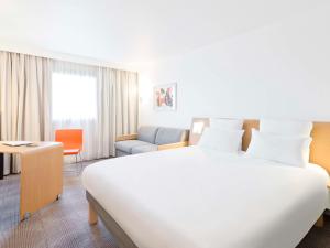 马尼·莱斯·阿莫Novotel Saint-Quentin en Yvelines的酒店客房设有一张白色大床和椅子