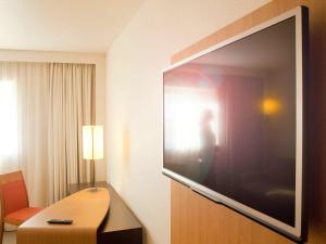 马尼·莱斯·阿莫Novotel Saint-Quentin en Yvelines的一间酒店客房墙上的大屏幕平面电视