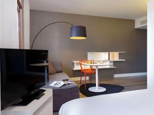 佩皮尼昂Novotel Suites Perpignan Centre的客房设有1张床、1张桌子和1台电视。