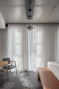 阿德莱德Vibe Hotel Adelaide的卧室配有白色窗帘、床和桌子