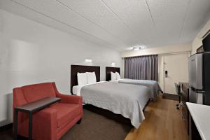 皮奥里亚Suburban Studios Peoria的酒店客房,配有一张床和一张红色椅子