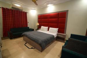 卡拉奇SEAVIEW COTTAGE的一间卧室配有一张带红色床头板的床和两把椅子