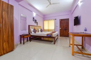 莫尔吉姆FabExpress Morjim Paradise的紫色墙壁客房里一间卧室,配有一张床