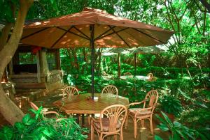 基苏木Desert Rose Resort Kisumu的一把伞下的木桌和椅子