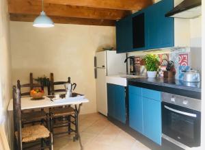 Lachapelle-sous-AubenasLa Petite Grange, pour un séjour écolo-chic !的厨房配有蓝色橱柜和桌子