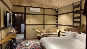 锡卡都Qayam Skardu的一间卧室配有一张床和两把椅子