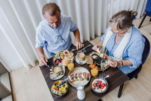 蒂伦豪特Corsendonk Turnova的坐在餐桌旁吃饭的男人和女人