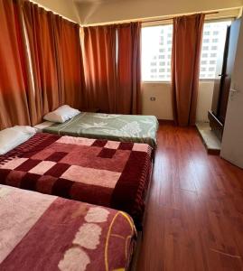 贝鲁特Rawche 30 Universal Apartments的配有红色窗帘的客房内的两张床