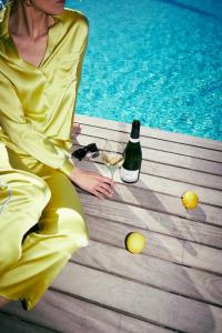 蒂鲁罗Hotel KÜGLERHOF的坐在一瓶酒旁边的穿着黄色衣服的女人