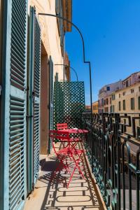 阿雅克修Hotel POZZO DI BORGO的阳台一侧的红色桌子