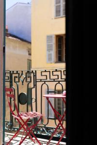 阿雅克修Hotel POZZO DI BORGO的阳台的红色桌子和椅子