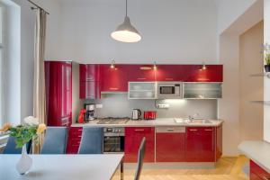 布拉格老城广场公寓的厨房配有红色橱柜和一张带蓝色椅子的桌子