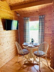 布罗德韦Keepers Lodges的一间带桌椅和电视的用餐室