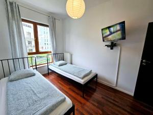 华沙FIRST -- Green Żoliborz apartment 3的客房设有两张床和一台平面电视。