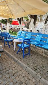 博兹贾阿达岛Ada Kalimera Bozcaada的一组蓝色的桌椅,放在伞下