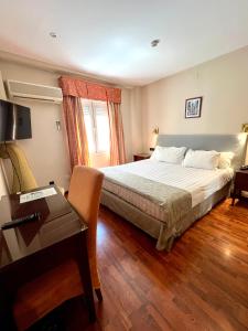 马拉加马拉加卡洛斯五世酒店的酒店客房配有一张床、一张书桌和一张书桌。