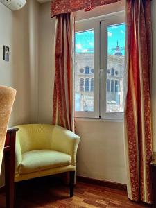 马拉加马拉加卡洛斯五世酒店的椅子和享有大楼景致的窗户