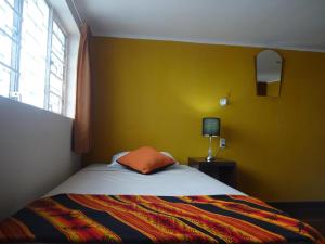 利马Sumaq Wasi Barranco II的一间卧室设有一张床和黄色的墙壁