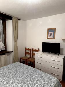 巴多尼奇亚Appartamento Bardonecchia的一间卧室配有一张床,梳妆台上配有电视