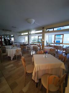 里米尼Hotel Prestige 3 Stars的餐厅设有白色的桌椅和窗户。