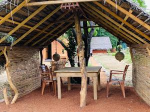 蒂瑟默哈拉默Yala Village Eco Tree House的木屋顶下的木桌和椅子