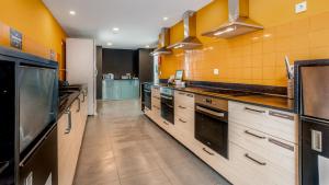 法鲁Hostellicious的一间设有黄色墙壁和不锈钢用具的大厨房