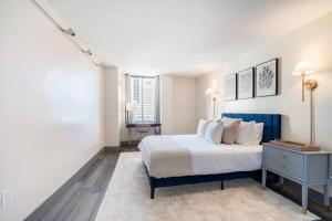 哈特福德Hartford Heights Skyline Views Await的一间卧室配有一张带蓝色床头柜的床和2扇窗户。