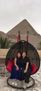 开罗Crystal pyramid inn的两个女人坐在金字塔前的椅子上