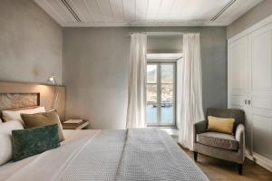 伊兹拉Hydrea Exclusive Hospitality的卧室配有床、椅子和窗户。