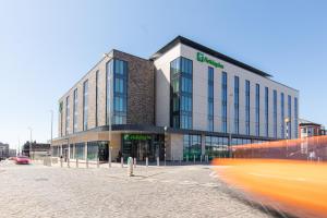 布莱克浦Holiday Inn Blackpool, an IHG Hotel的街道上的建筑物,前面有一辆公共汽车