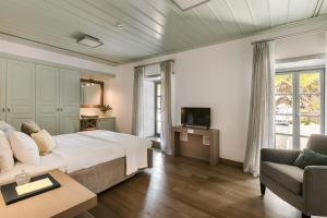 伊兹拉Hydrea Exclusive Hospitality的一间卧室配有一张床、一张沙发和一台电视。