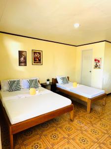 马拉帕斯加Edem Tourist Inn Malapascua的配有两张床铺的黄色墙壁客房