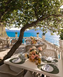 伏罗拉Hotel Liro - Adults Only的海滩上一张桌子上放着盘子和鲜花