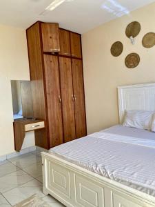 蒙巴萨Graceful Listing的卧室配有白色的床和木制橱柜。