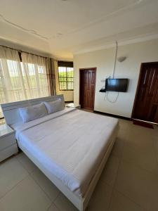 金贾Marina Lake View Apartments,Jinja的卧室配有一张大床,墙上配有电视