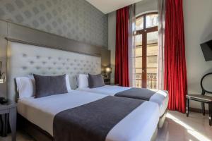 巴塞罗那巴塞罗那梅诺卡酒店的配有红色窗帘的酒店客房的两张床